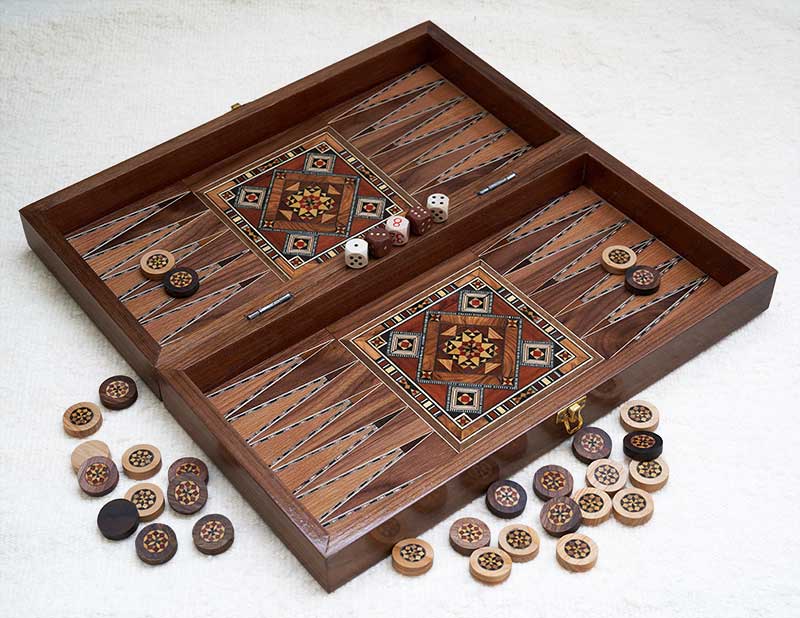 L'intérieur du coffret de marqueterie » Table Magique « montrant le tablier de backgammon avec des pions en marqueterie pour le jeu ainsi qu'un jeu de dés